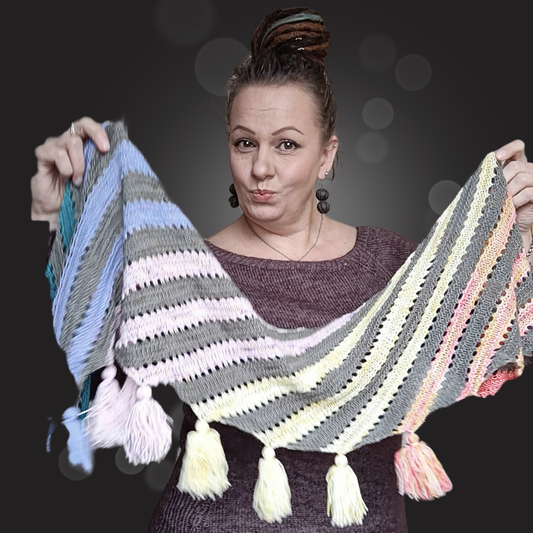 Neulottu Joy of Stripes -huivi levitettynä, värikkäitä vinoraitoja eri sävyissä – hauska ja iloinen tapa hyödyntää lankajämät.