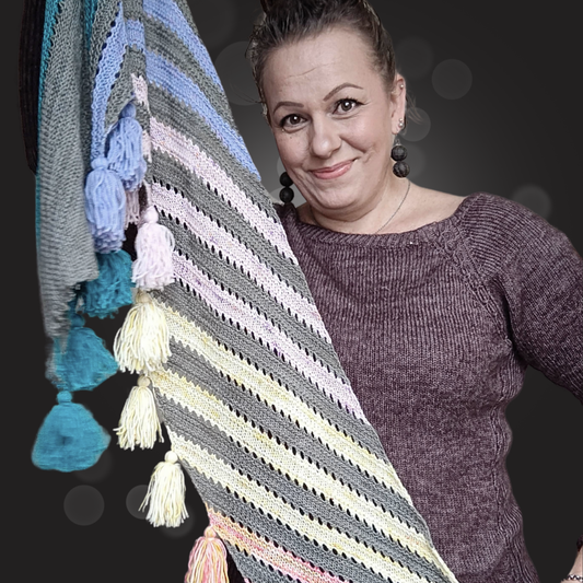 Neulottu Joy of Stripes -huivi levitettynä, värikkäitä vinoraitoja eri sävyissä – hauska ja iloinen tapa hyödyntää lankajämät.