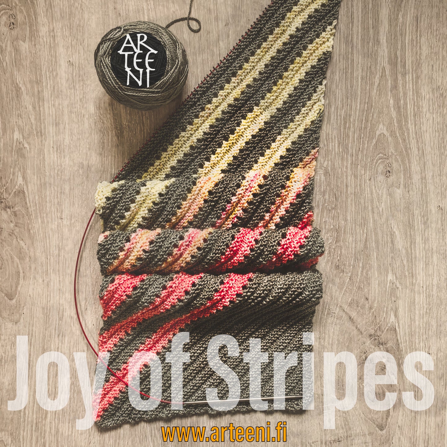 Neulottu Joy of Stripes -huivi levitettynä, värikkäitä vinoraitoja eri sävyissä – hauska ja iloinen tapa hyödyntää lankajämät.